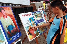 小朋友駐足在伊達邵碼頭上的法輪功真相展板前討論
