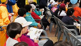 '來參加當天活動的市民接收法輪功傳單了解真相，並在聲援法輪功反迫害的簽名欄上簽名。'