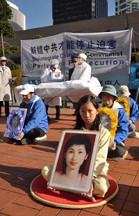 '新西蘭法輪功學員在奧克蘭市中心舉辦揭露中共十二年迫害，呼籲制止迫害的活動。圖為法輪功小學員開心懷抱媽媽的遺像在活動中。開心的母親羅織湘女士因為修煉法輪大法被惡警抓捕十二天後遭迫害致死'