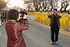 很多遊客以法輪功功法演示團為背景拍照留念