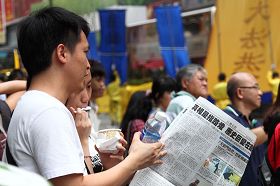 學員們派發的真相資料大受歡迎，民眾一邊觀看遊行，一邊閱讀特刊