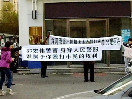 法輪功學員李方芳和朱蘭英的家人在派出所門外打出條幅譴責警察打人
