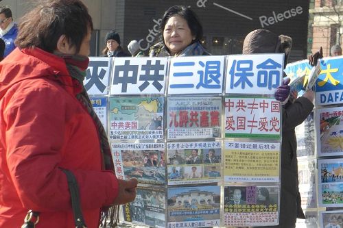 紐約自由女神像附近，法輪功學員向遊客展示真相展板。
