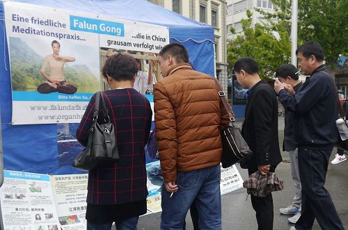 '圖5：中國遊客看展板了解真實的法輪功，並拍照留念'