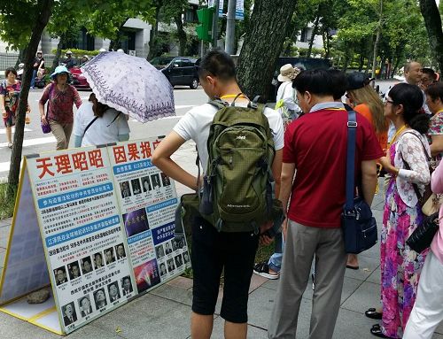 圖：國父紀念館外，大陸遊客認真閱讀法輪功真相展板