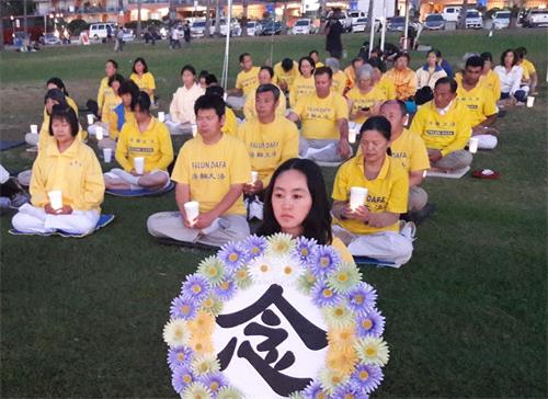 '圖8～9：夜幕降臨之際，法輪功學員們手持燭光排坐在草坪上舉行燭光夜悼'