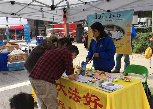 '圖1：法輪功學員參加紐約州府奧伯尼雲雀節。圖為人們簽名支持法輪功反迫害。'