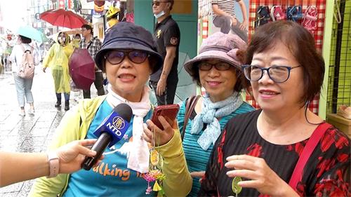 '圖5～6：很多遊客爭先拿取印有「法輪大法好、真善忍好」的精美蓮花紀念品，得到蓮花的民眾欣喜雀躍，彷若拿到吉祥如意的護身符，連連稱謝。'