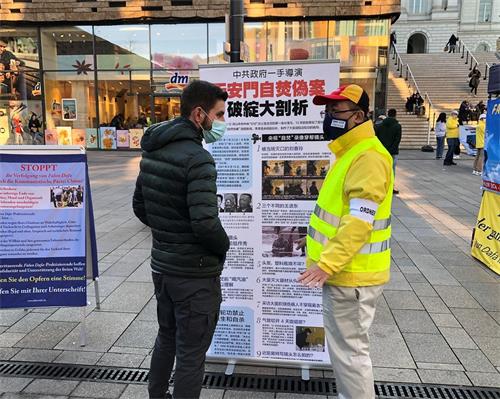 '圖7：一位路人在展板前聽法輪功學員講真相'