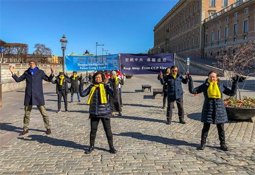 '圖3：法輪功學員伴隨著煉功音樂向路人演示法輪功的五套功法。'