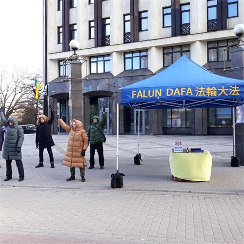 '圖2：法輪功學員在老城市中心搭起真相展位並展示功法'