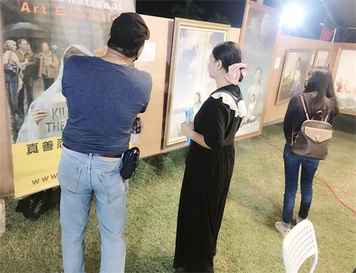 '圖2、4、7：人們駐足欣賞法輪功學員的畫作，了解真相'